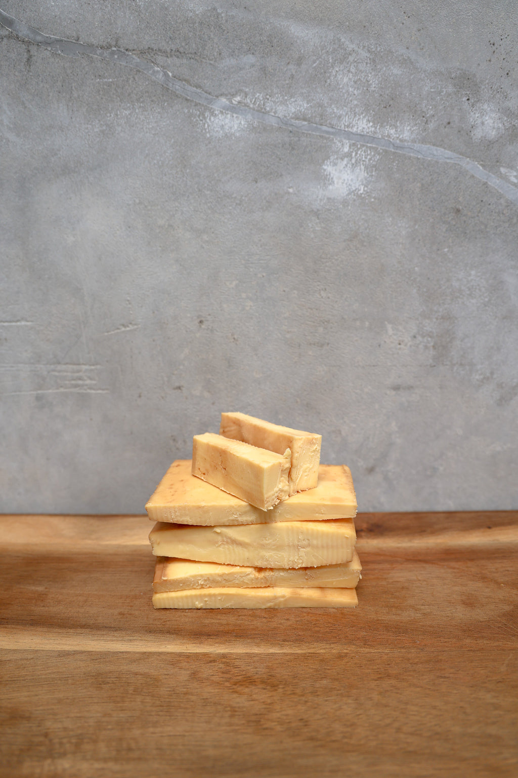 Packaged Smoked Havarti Offcuts from Eltham Cheese Bar on a wooden surface with a concrete wall background