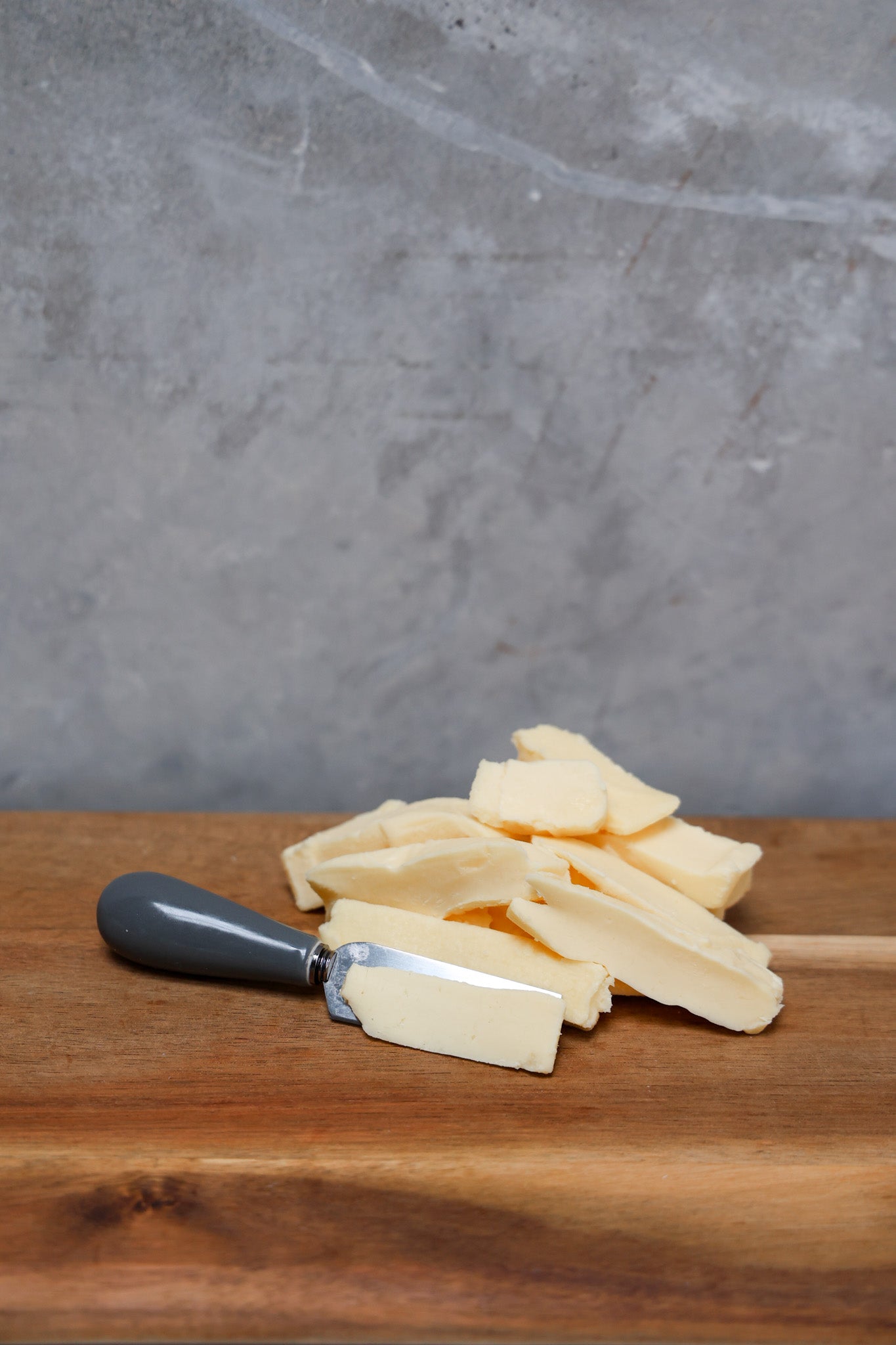 Stack of Havarti Offcuts from Eltham Cheese Bar on a wooden surface with a gray concrete background