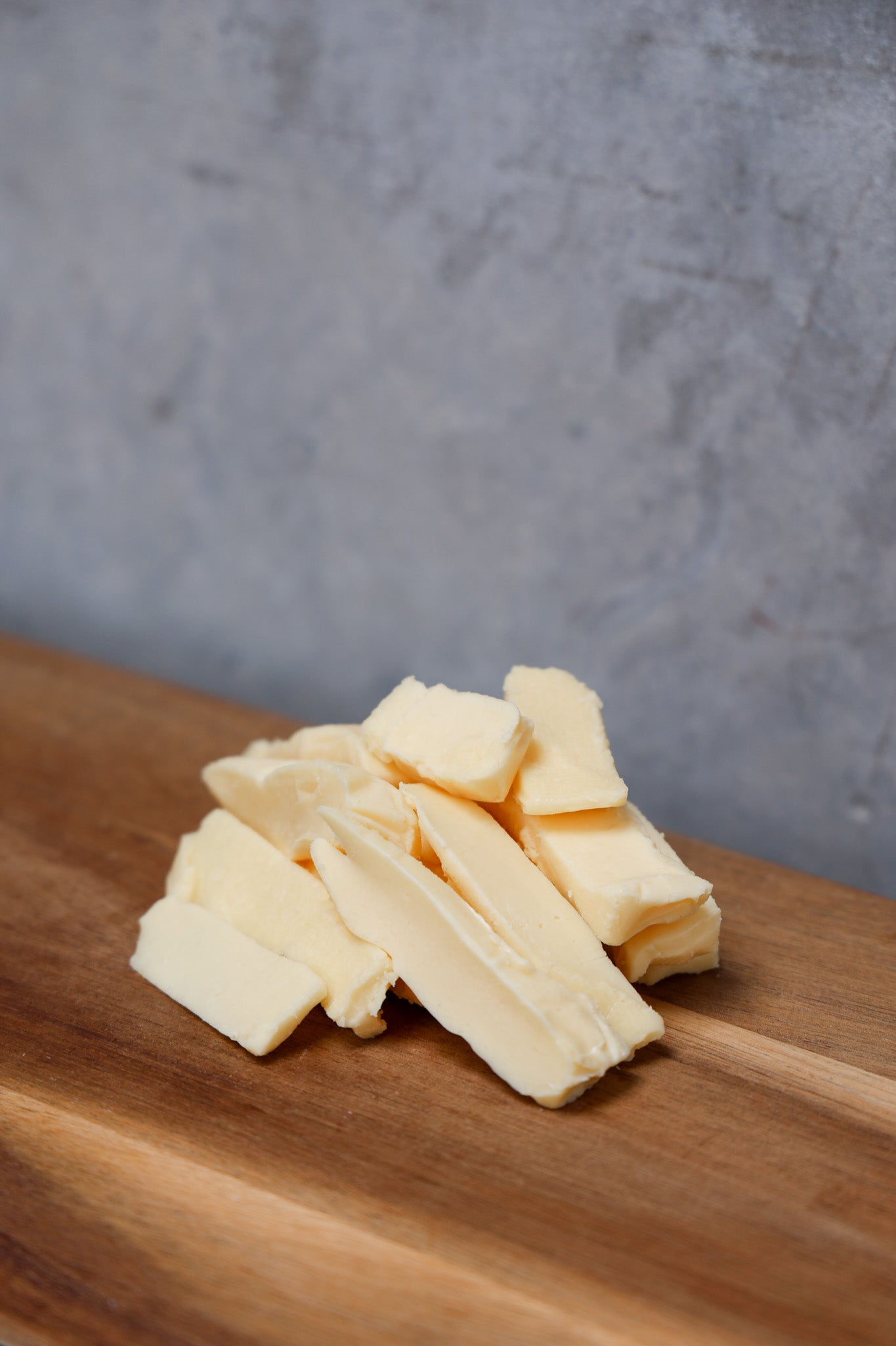 Stack of Havarti Offcuts from Eltham Cheese Bar on a wooden surface with a gray concrete background