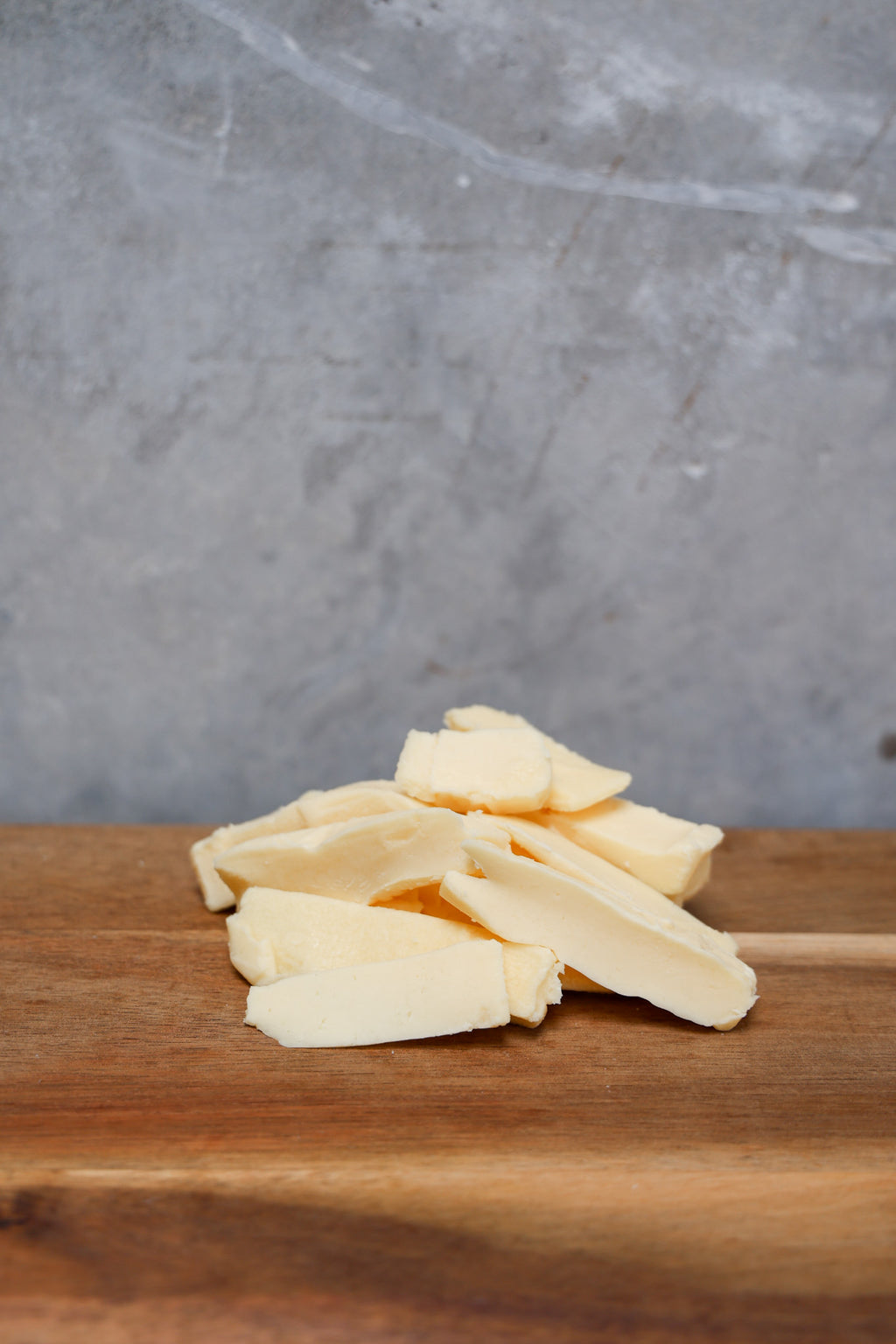Stack of Havarti Offcuts from Eltham Cheese Bar on a wooden surface with a gray concrete background