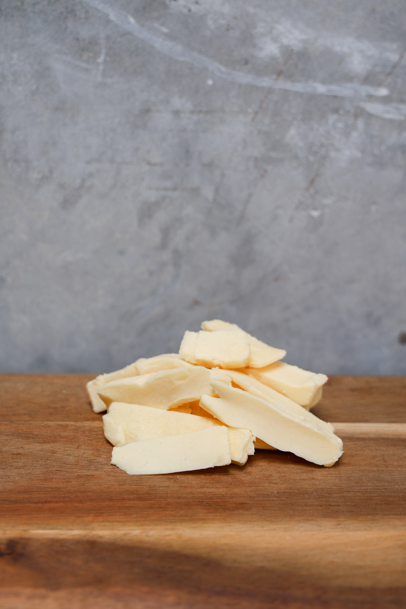 Stack of Havarti Offcuts from Eltham Cheese Bar on a wooden surface with a gray concrete background