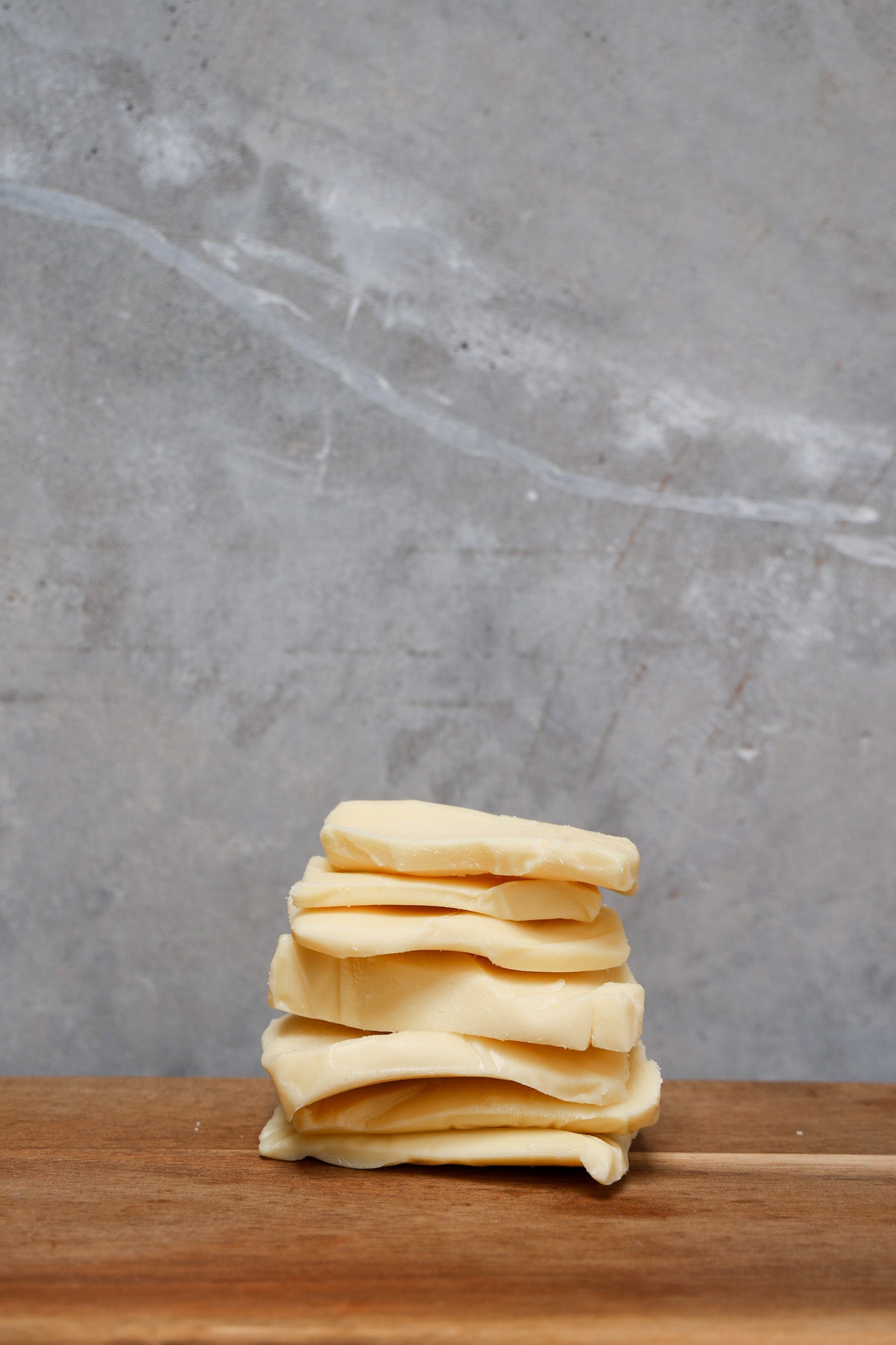 Stack of Mozzarella Offcuts from Eltham Cheese Bar on a wooden surface with a gray concrete background