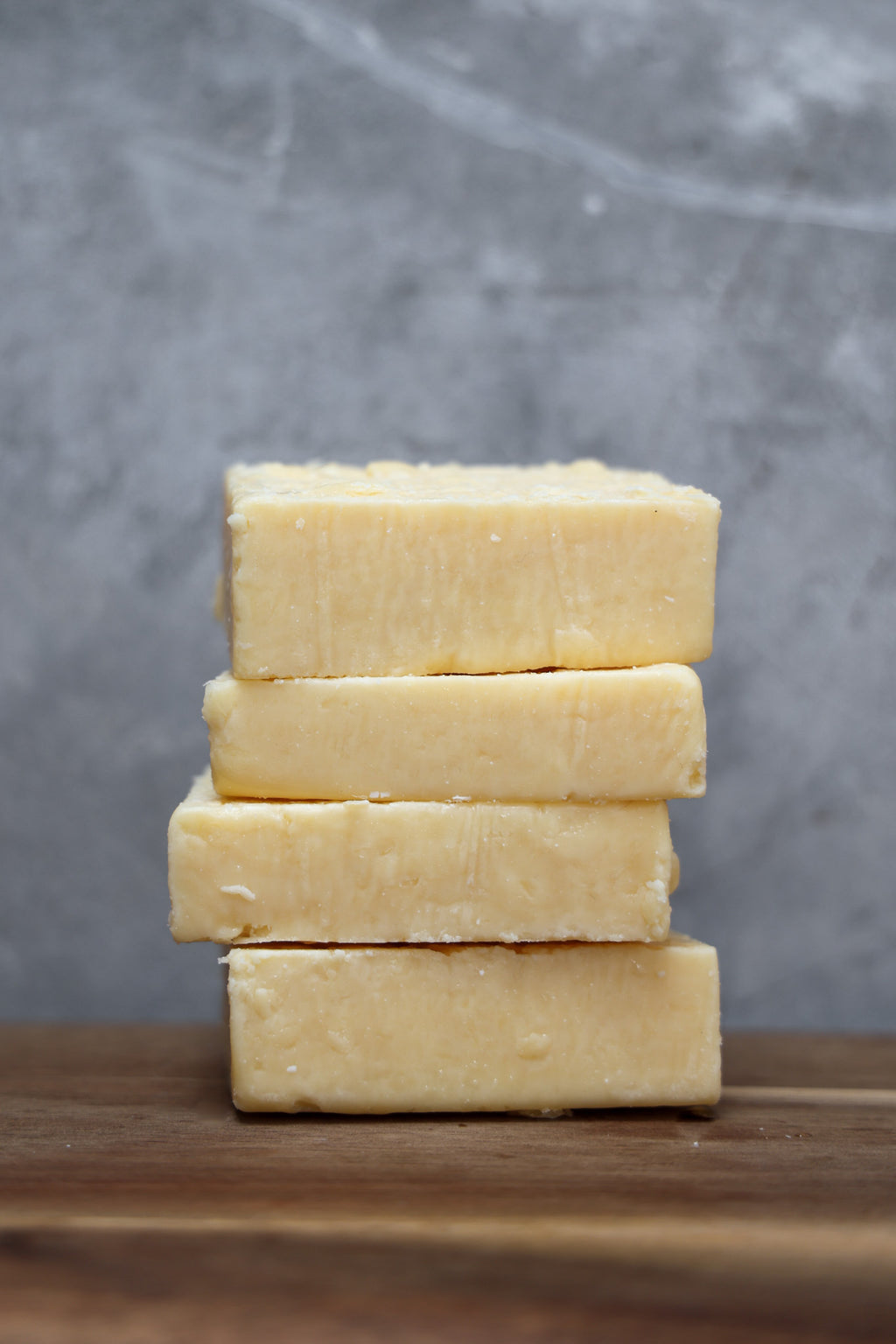 Stack of parmesan cheese from Eltham Cheese Bar on a wooden surface with a gray background